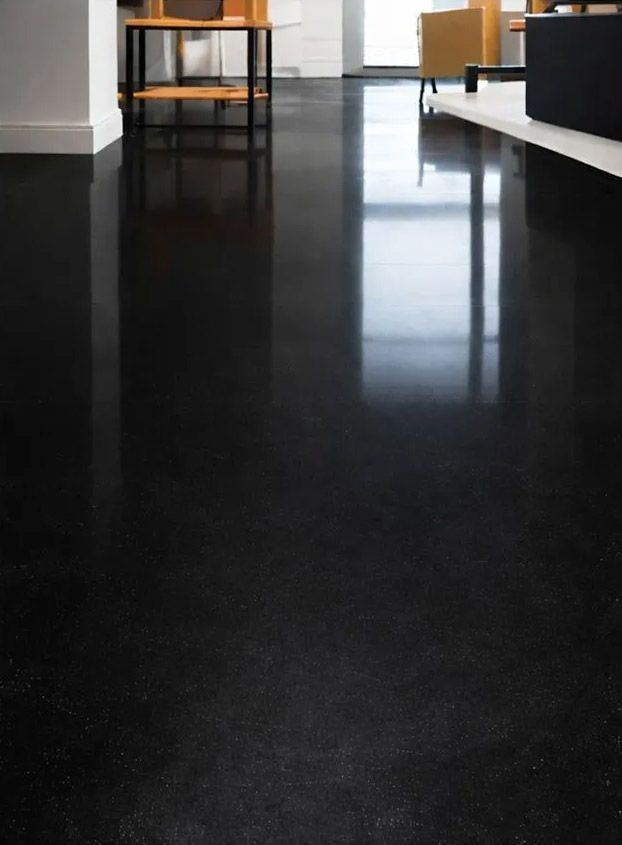 El suelo negro pulido refleja la luz y el mobiliario interior.