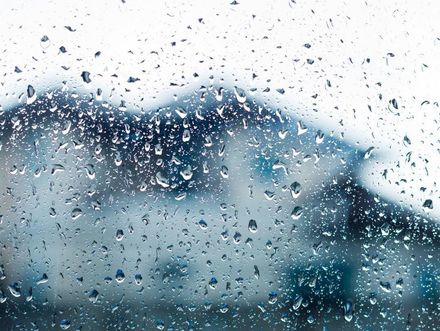 Un primer plano de gotas de lluvia en una ventana con una montaña al fondo.