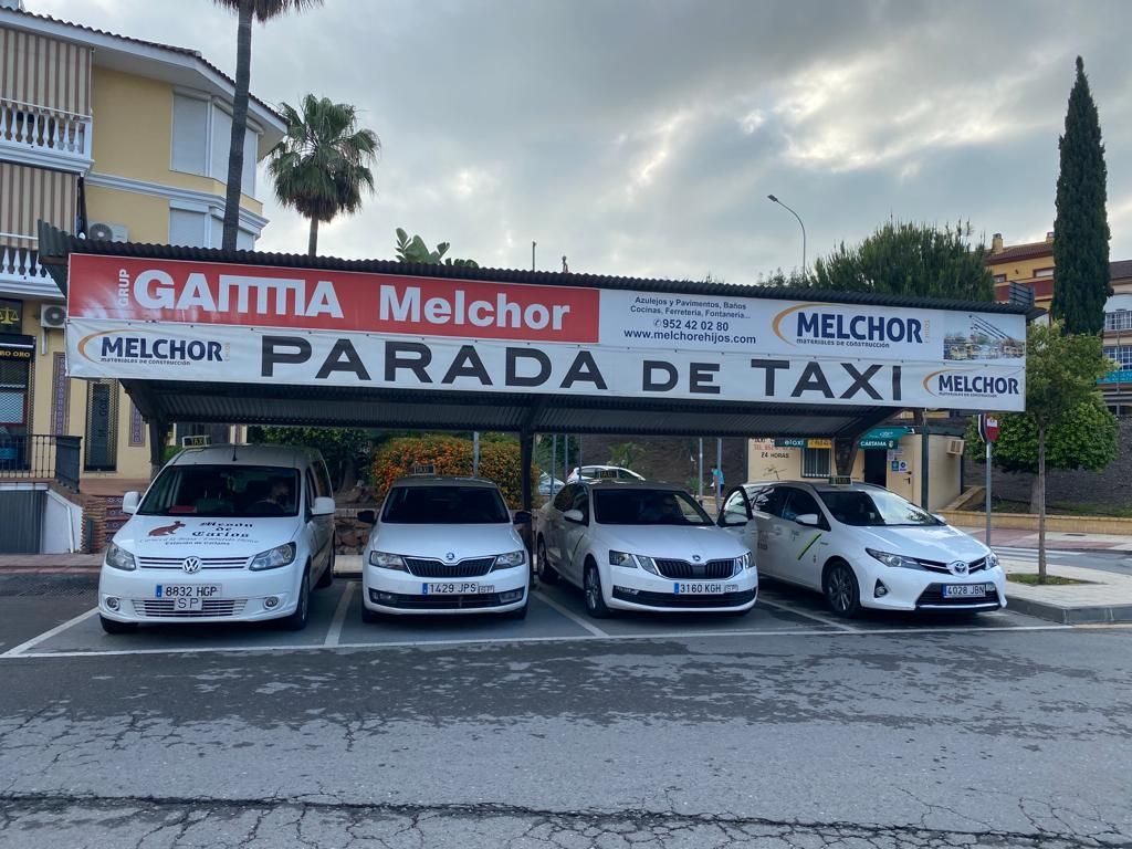 Cuatro taxis estacionados bajo un toldo de parada de taxis con la inscripción 