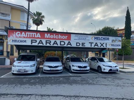 Cuatro taxis estacionados bajo un toldo de parada de taxis con la inscripción 