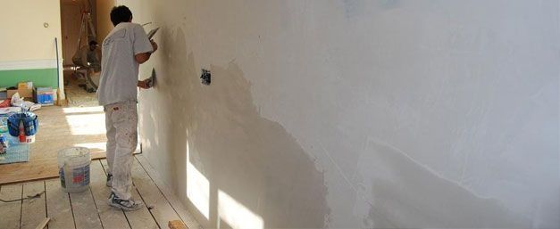 Un hombre está pintando una pared en una habitación.