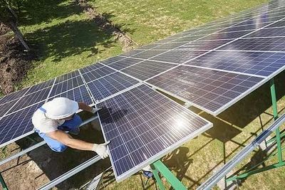 Un trabajador limpia los paneles solares de una azotea con un cepillo azul.