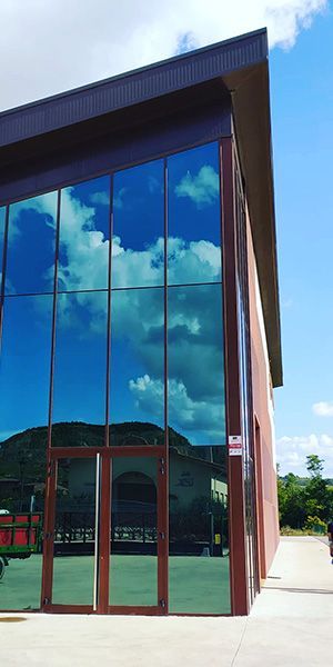 Un gran edificio con muchas ventanas y un cielo azul reflejado en las ventanas.
