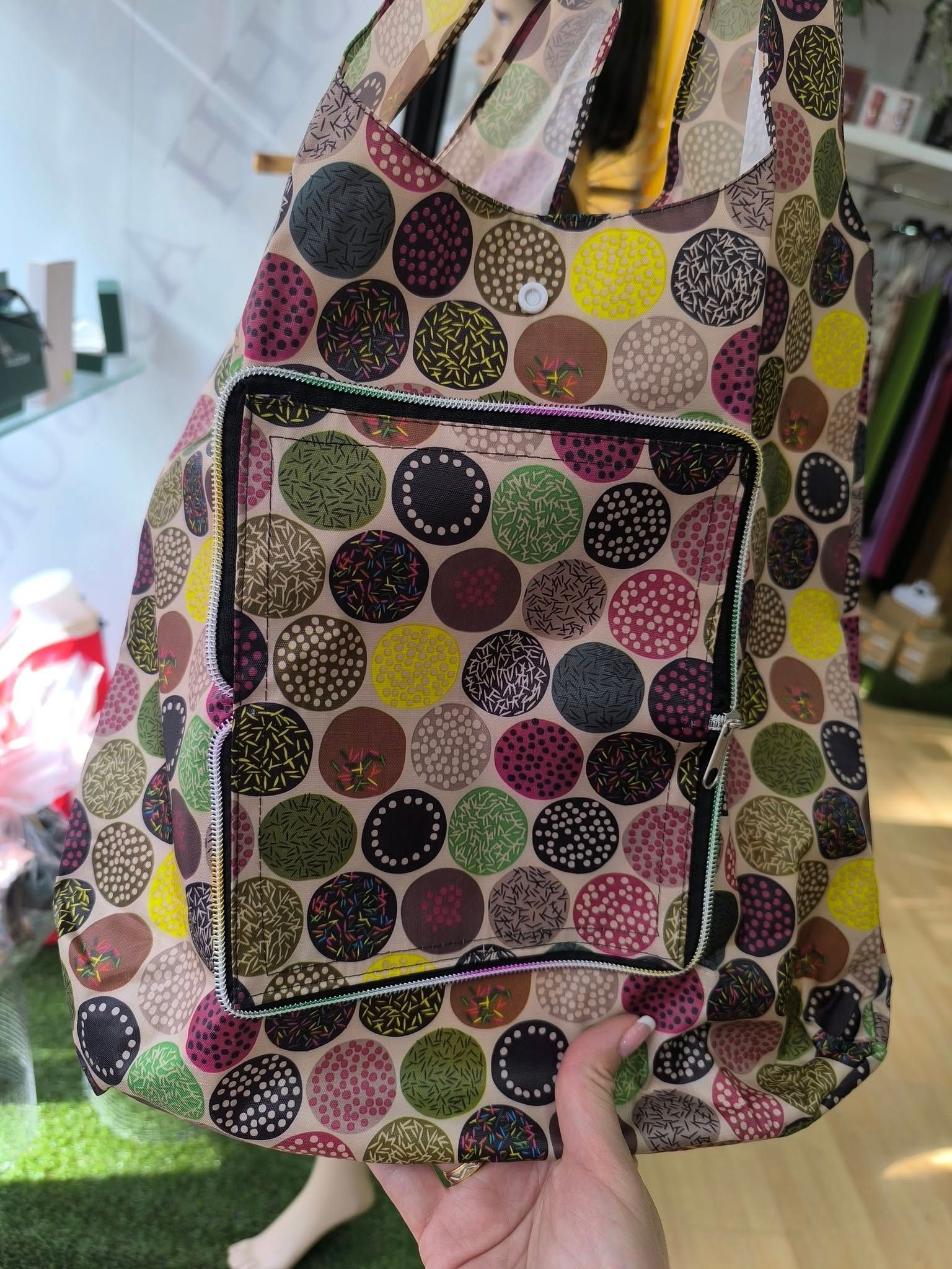 Una persona sostiene una mochila colorida con lunares.