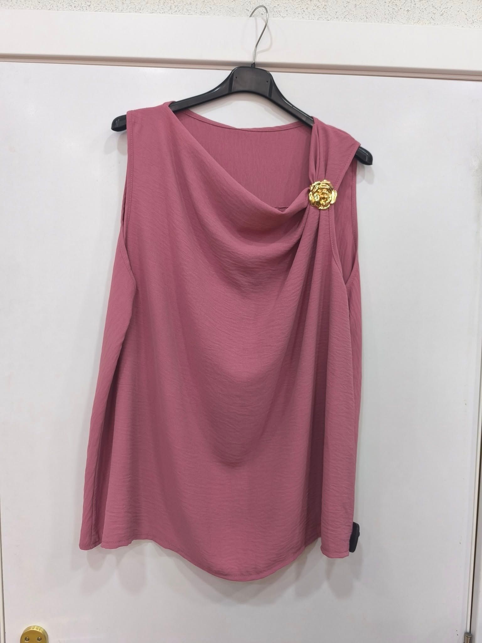 Un top rosa está colgado en una percha en una puerta blanca.