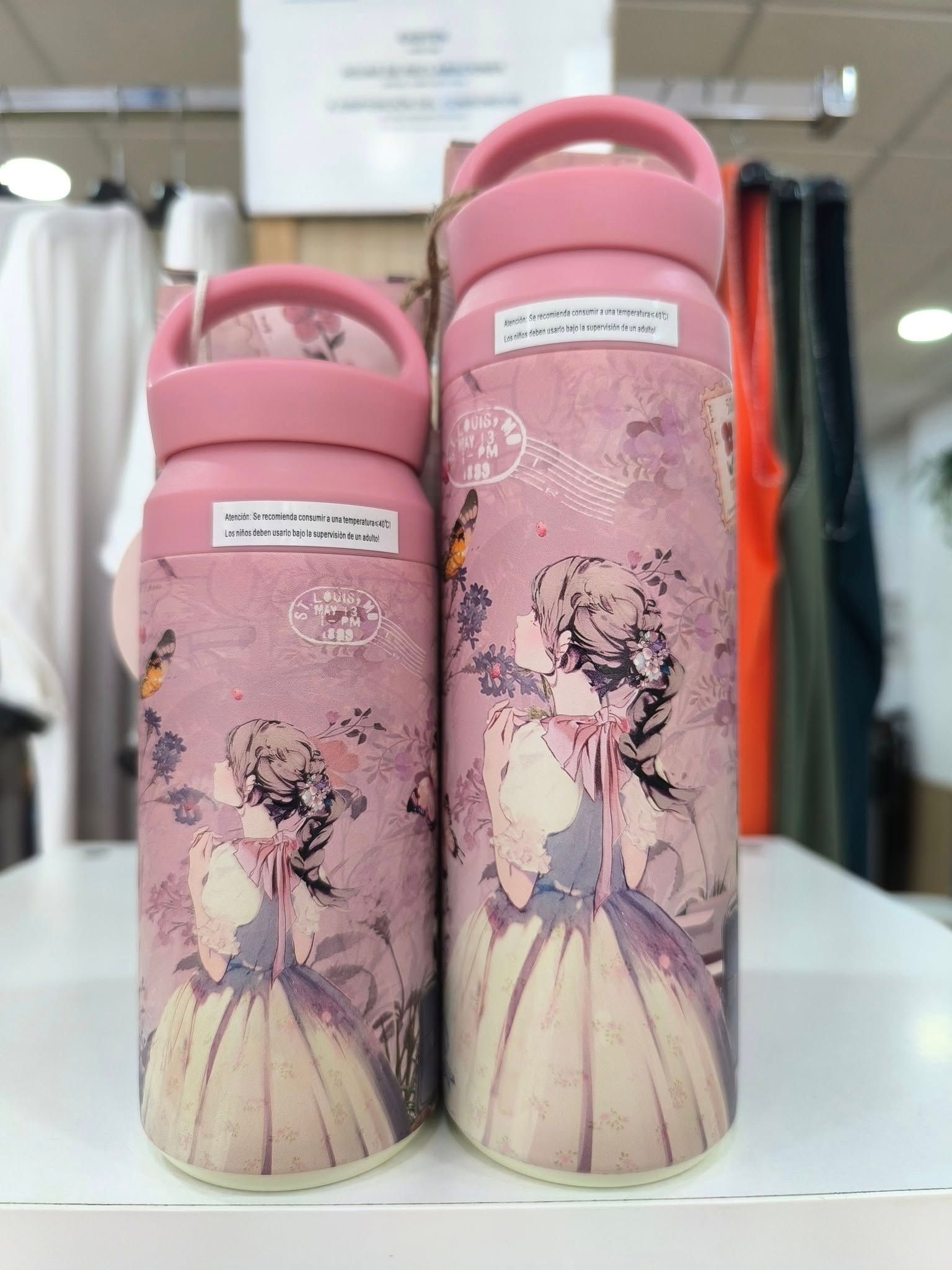 Dos botellas rosas con una imagen de una mujer en ellas están sobre una mesa.