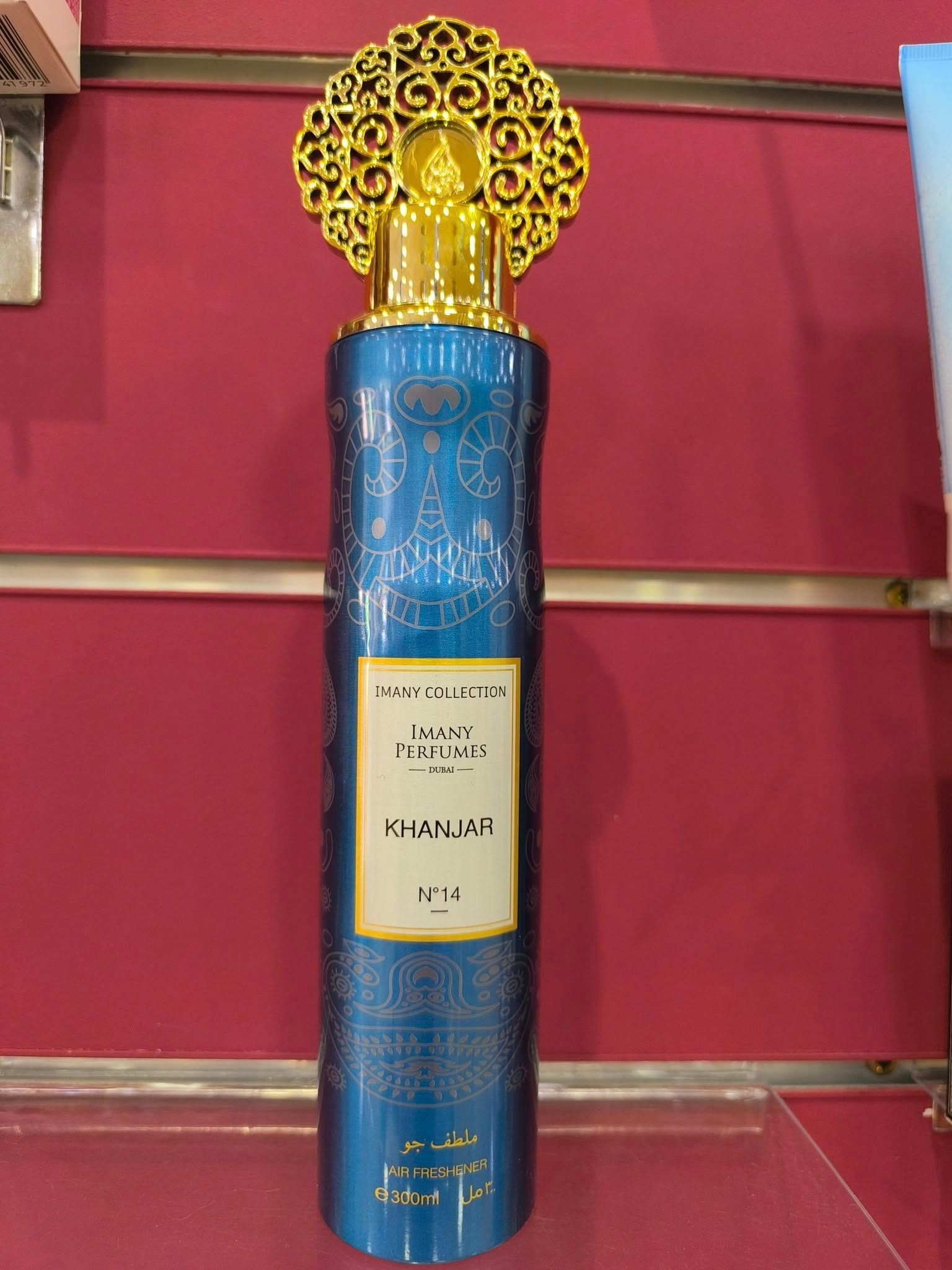 Una botella de perfume azul está sobre una pared roja.