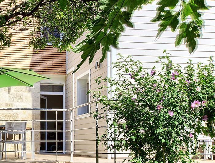 Pavillon avec bardage lames et plantes devant.