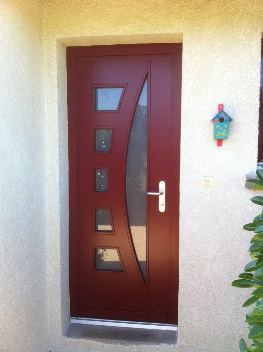 Porte d'entrée rouge avec plusieurs vitres réfléchissantes.