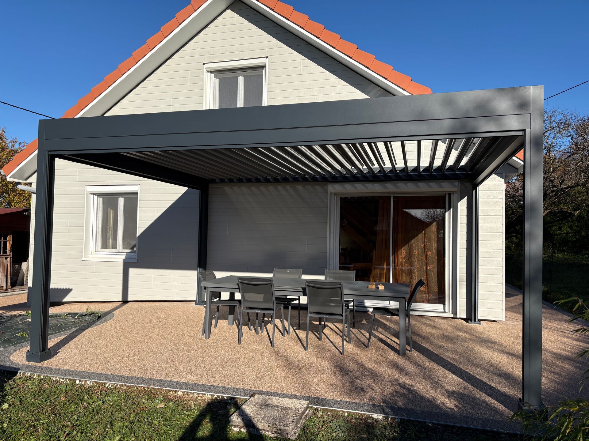 Pergola sur une terrasse avec table et chaises.