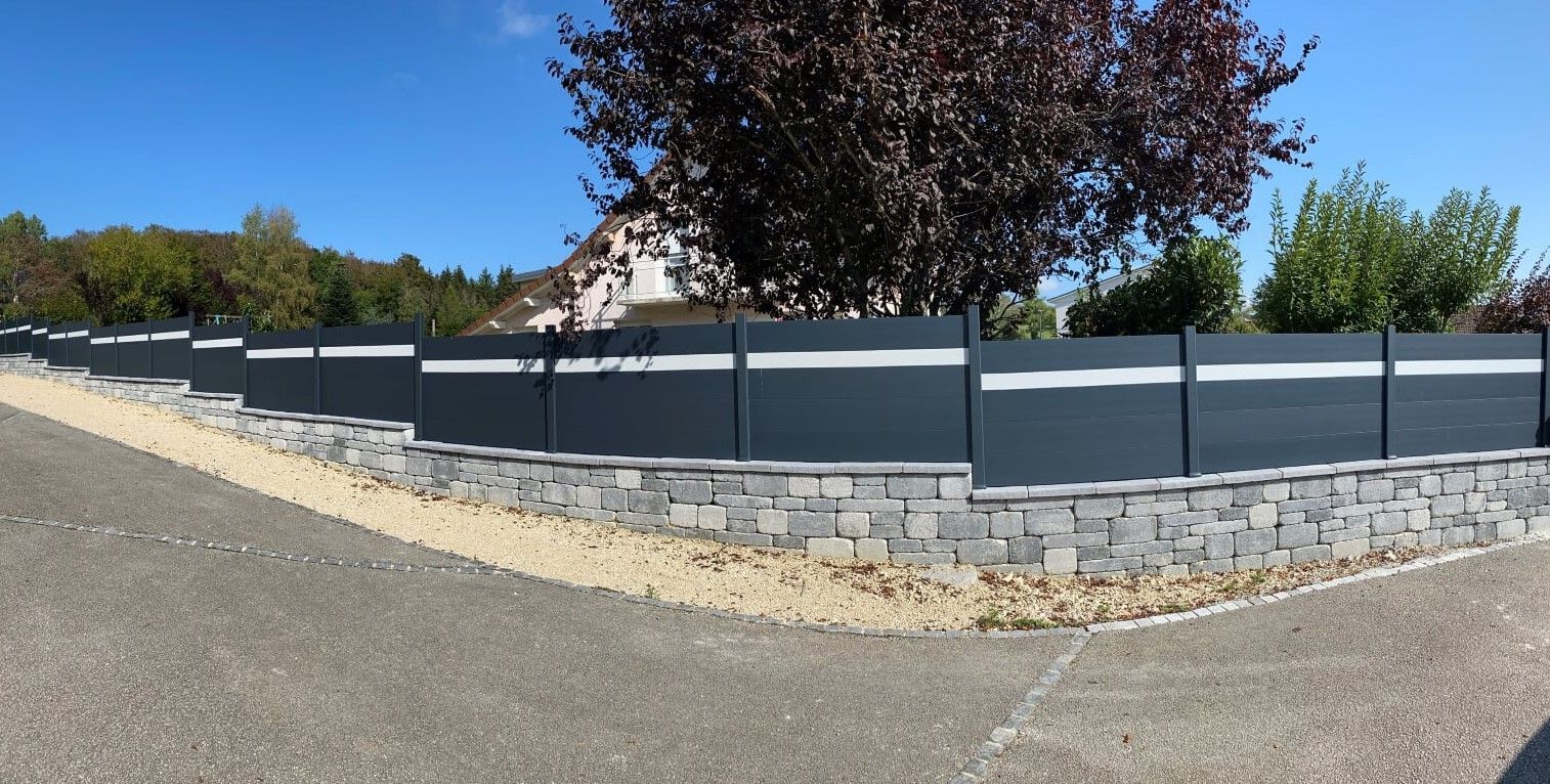 Clôture opaque sur un muret en pierre.