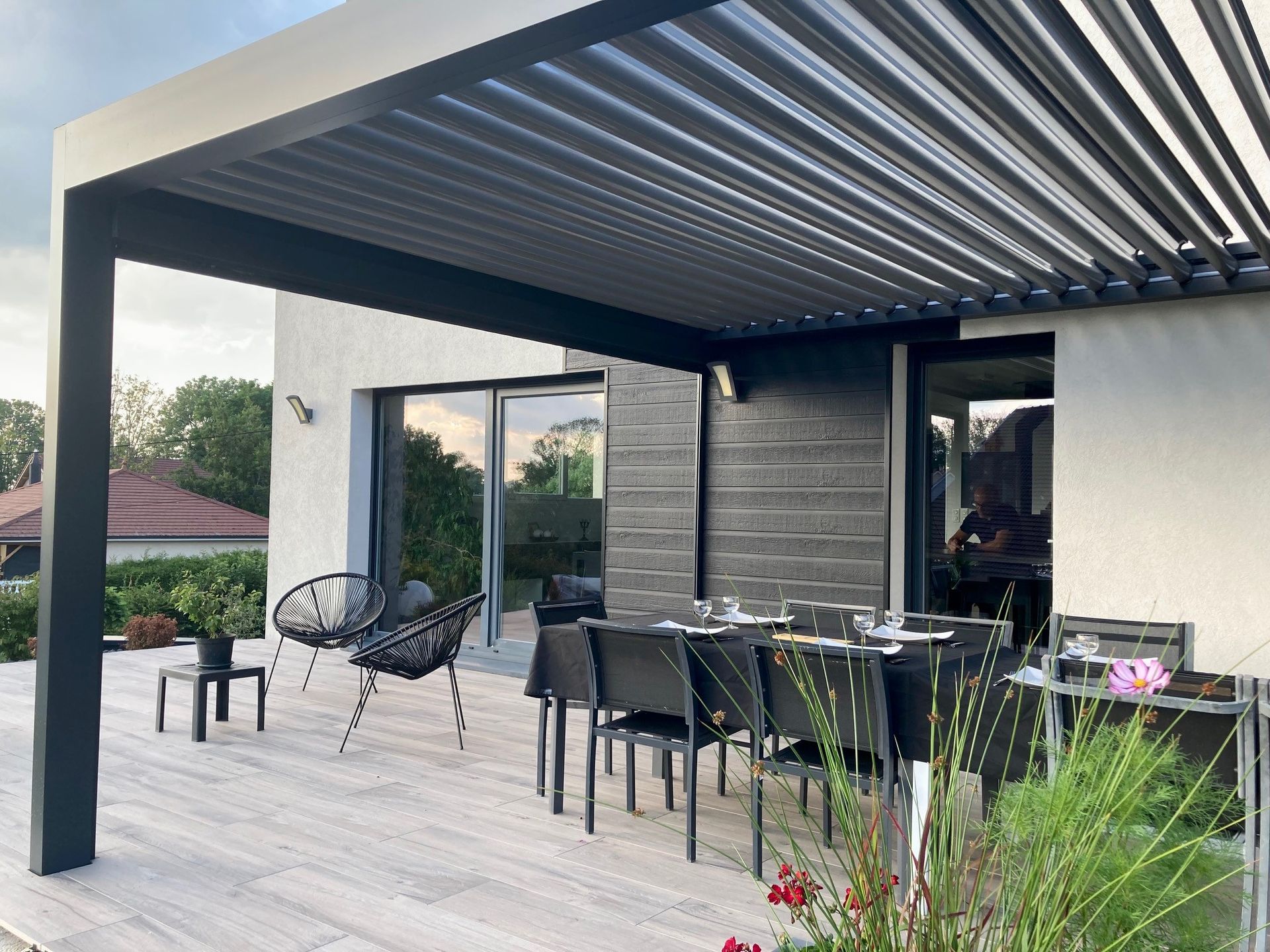 Sièges et table sur une terrasse sous une pergola.
