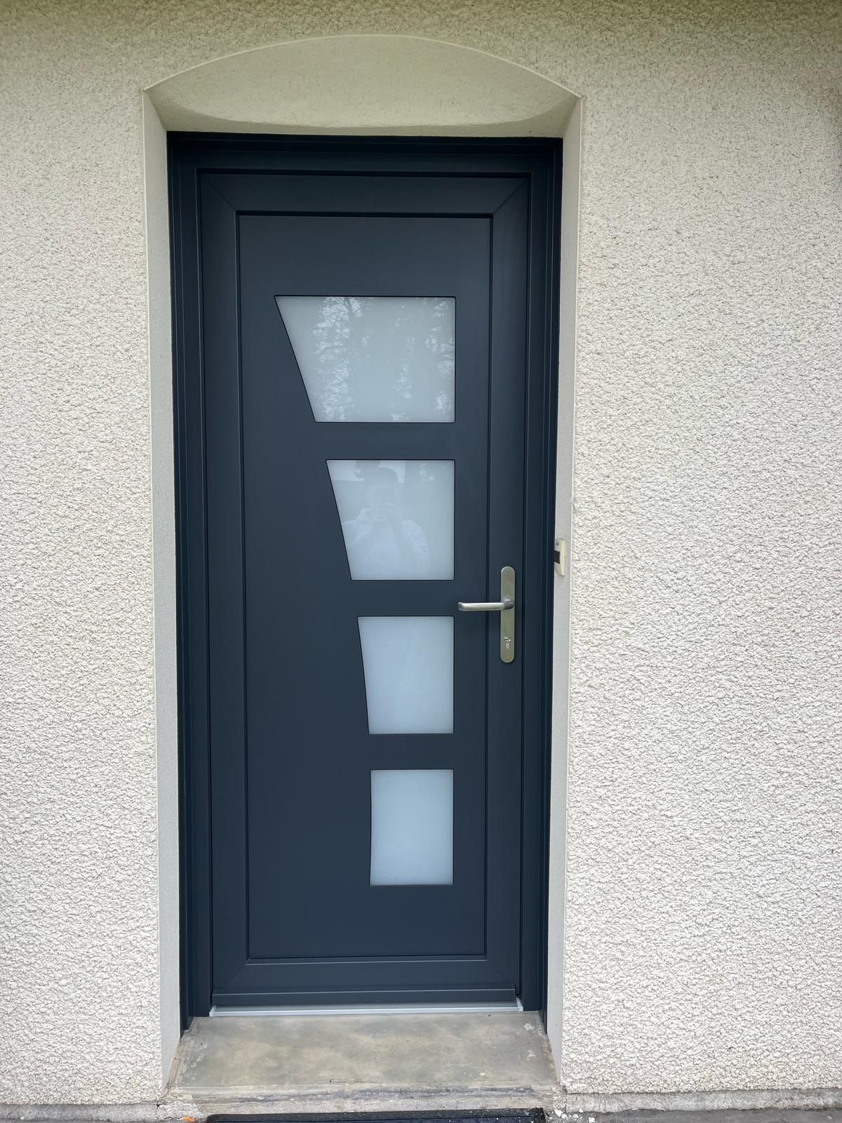 Porte d'entrée bleu sombre avec quatre vitres.