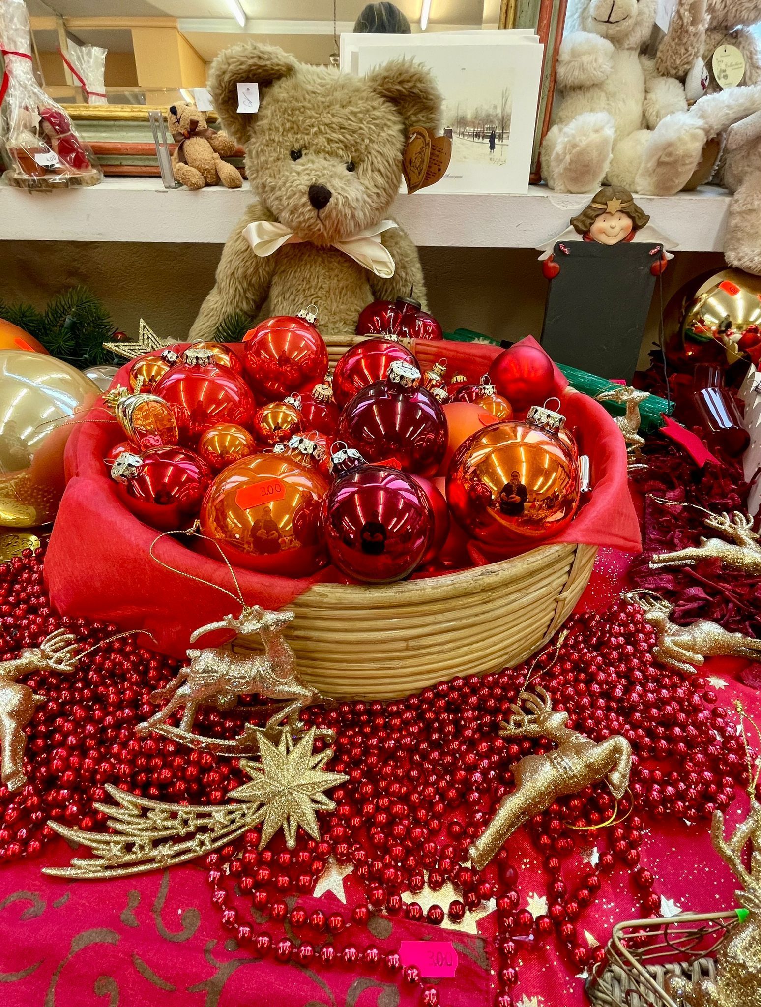 Ein Teddybär sitzt in einem Korb mit Weihnachtsdekorationen.