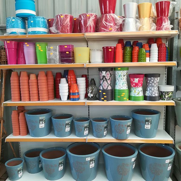 Un estante lleno de macetas de muchos colores diferentes.