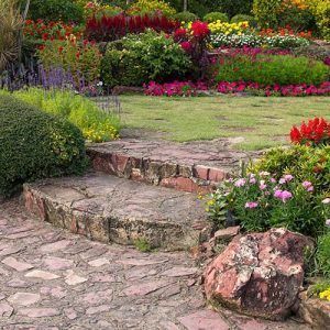 Un camino de piedra que conduce a un jardín lleno de flores y plantas.