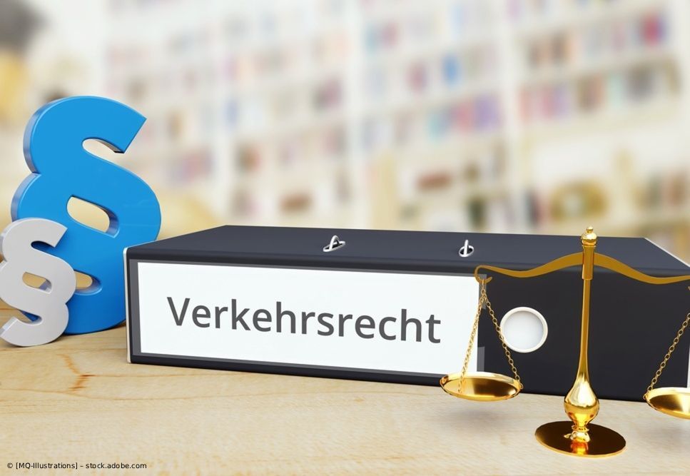 Auf einem Schreibtisch liegt ein schwarzer Ordner mit der Aufschrift „Verkehrsrecht“ neben Rechtssymbolen