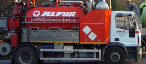 Un camión rojo de combustible múltiple está estacionado al costado de la carretera.
