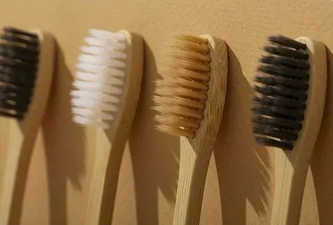 Una fila de cepillos de dientes de madera con cerdas diferentes están alineados sobre una mesa.