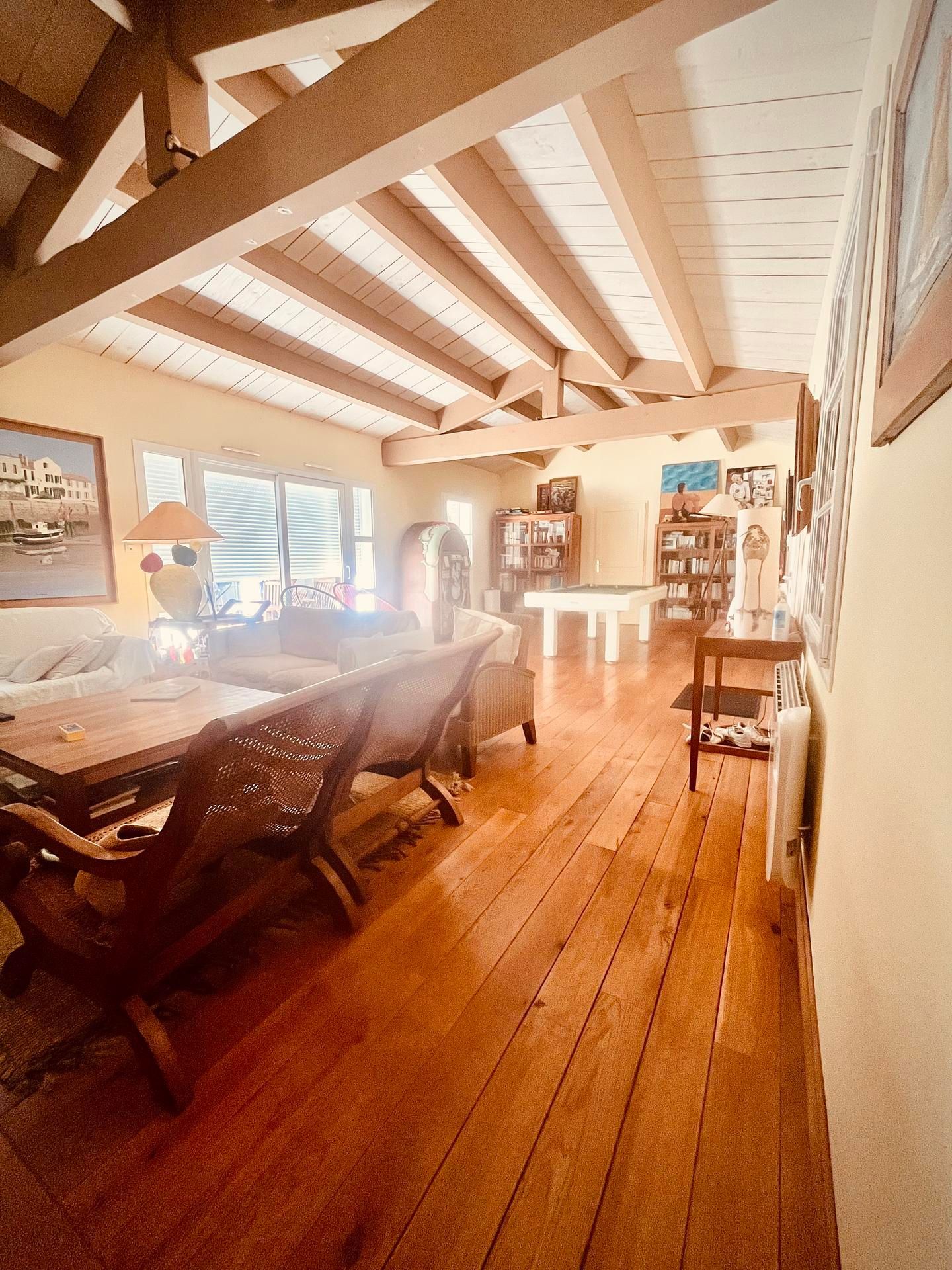 Séjour avec parquet et poutres apparentes.