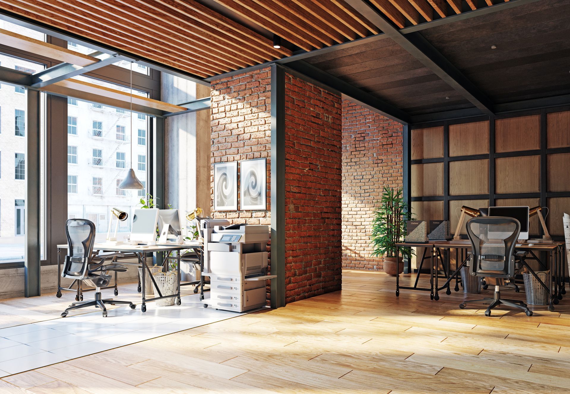 Intérieur de bureau moderne avec postes de travail, murs en briques et grandes fenêtres.