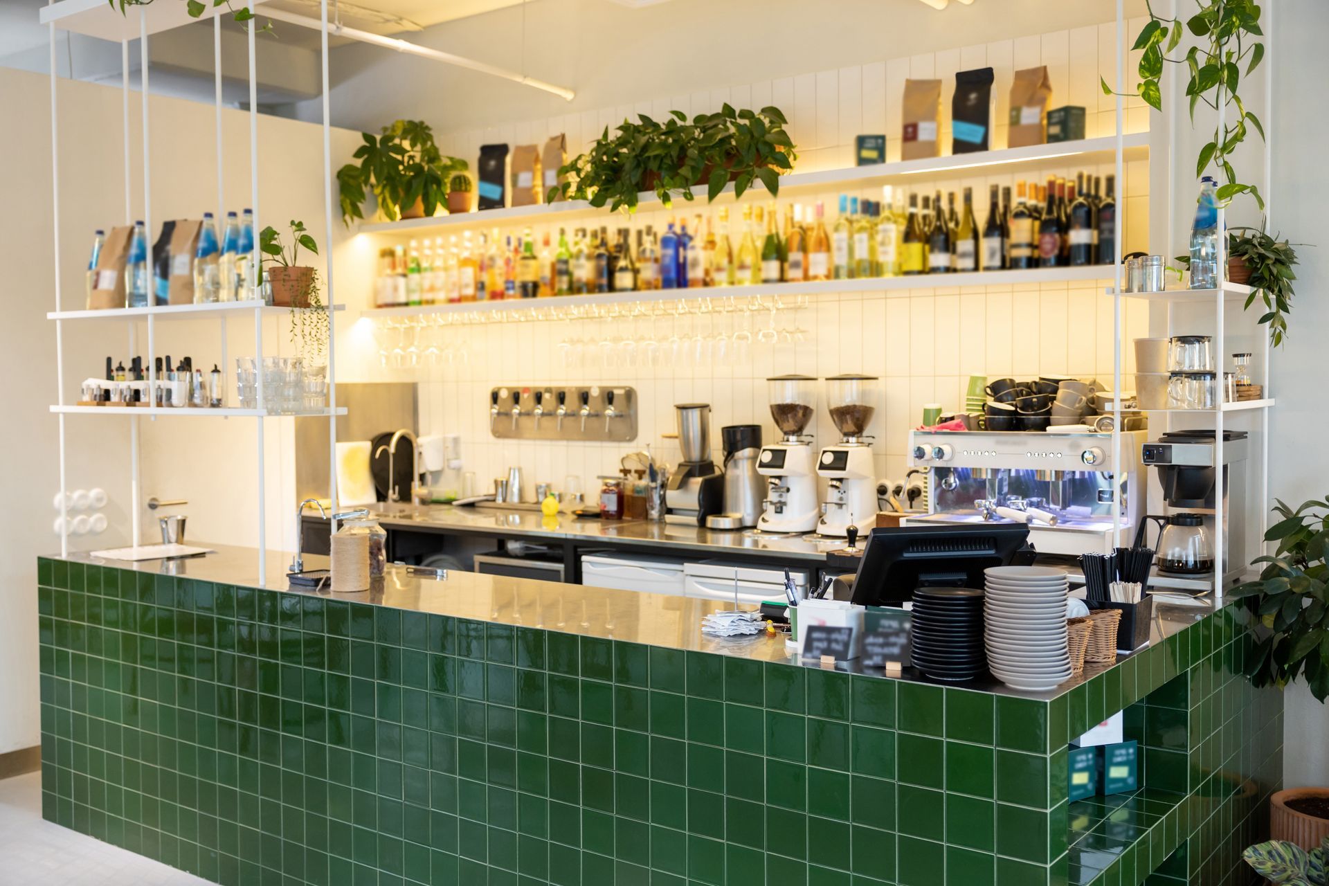 Comptoir de café carrelé vert avec étagères de boissons.