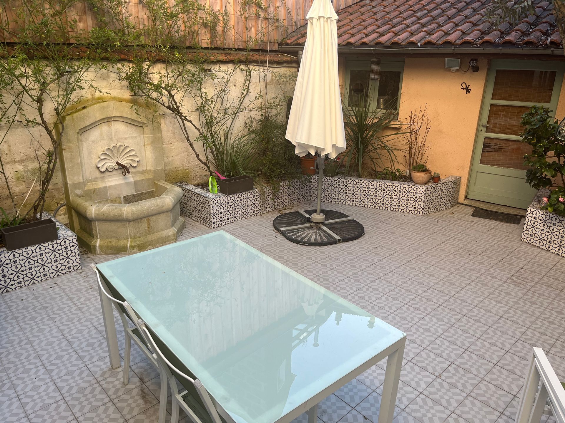 Patio avec table en verre et fontaine.