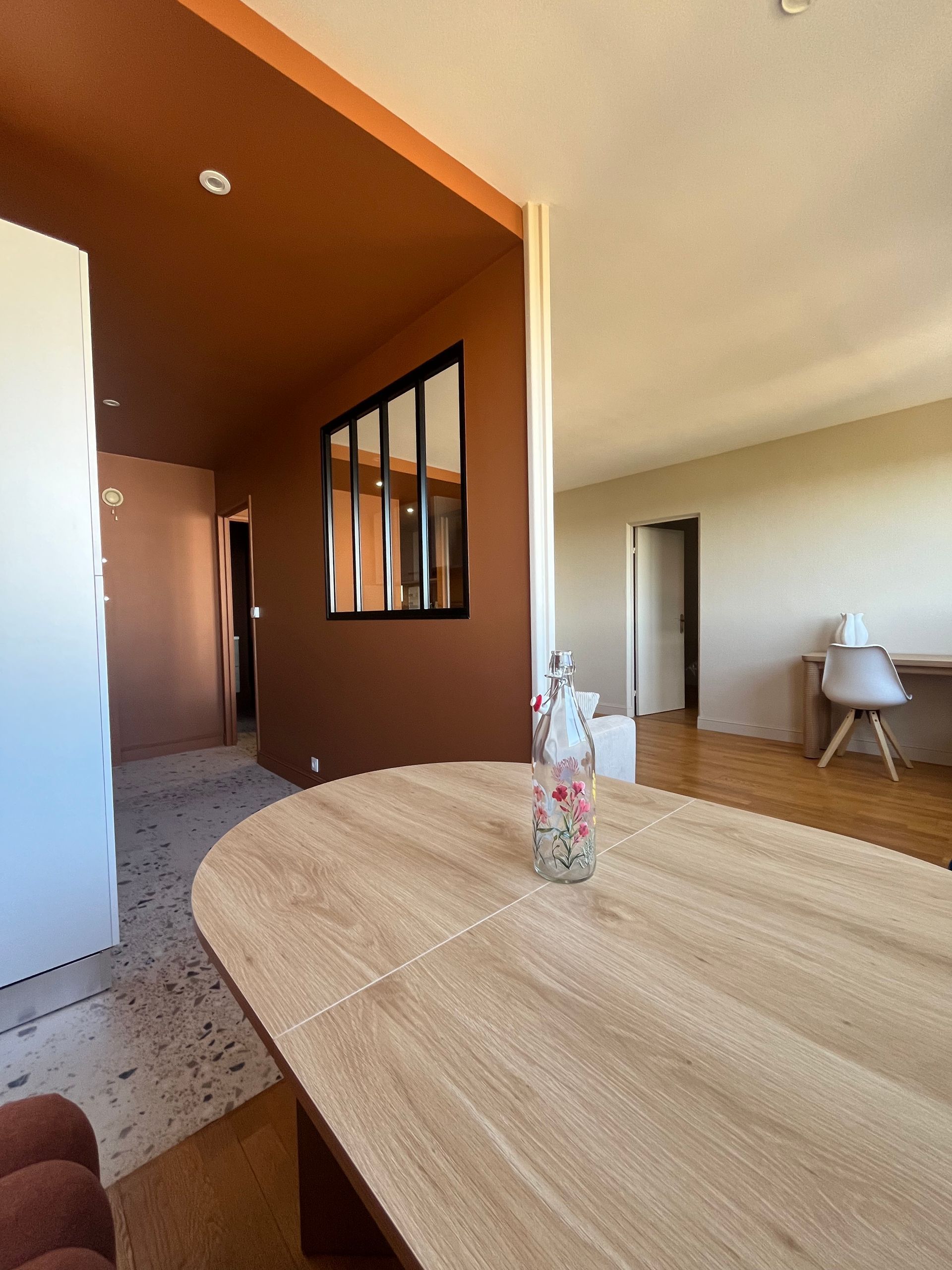 Salle à manger moderne à aire ouverte avec une table en bois, un mur d’accent brun et un vase en guise de centre de table