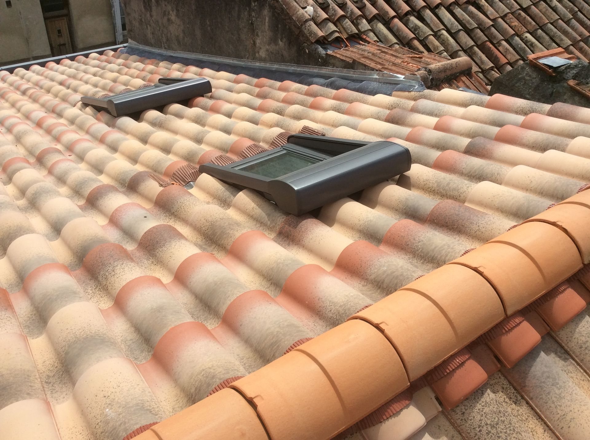 Toiture en tuiles de terre cuite avec deux lucarnes.