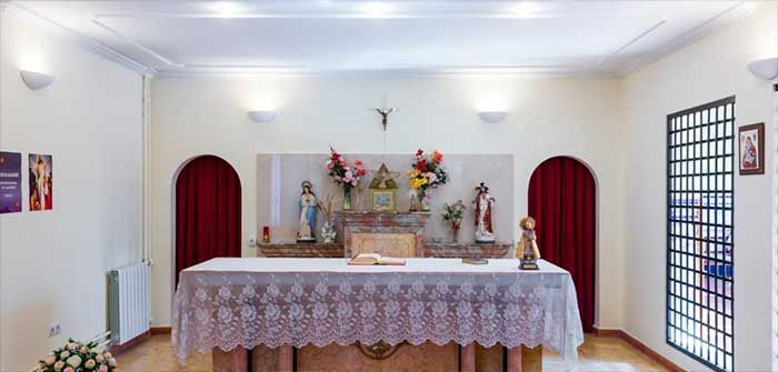 Una iglesia con una mesa y una cruz en la pared.