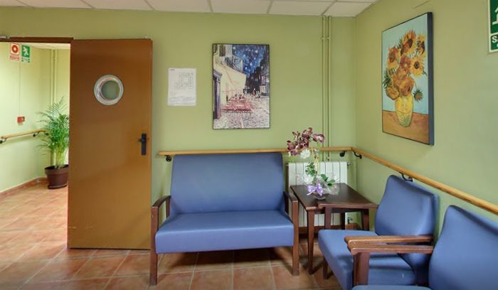 Una sala de espera con un sofá y sillas y un cuadro en la pared.