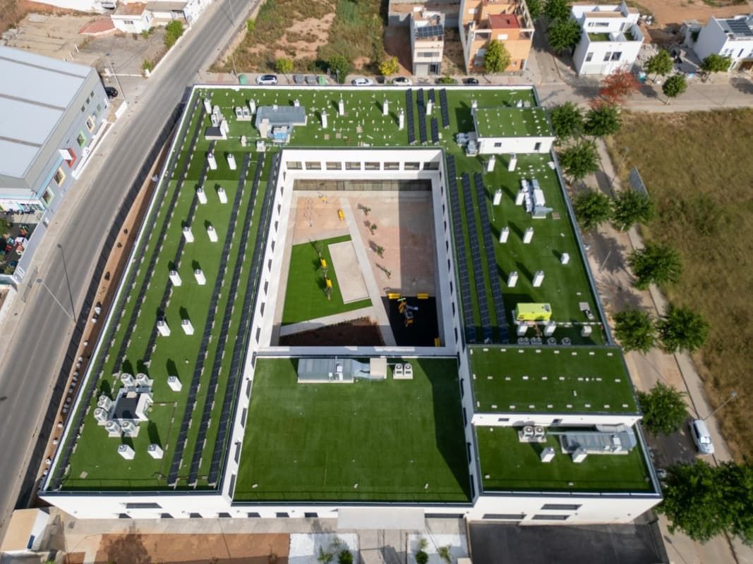 Vista aérea de un edificio moderno con azotea verde y patio central.