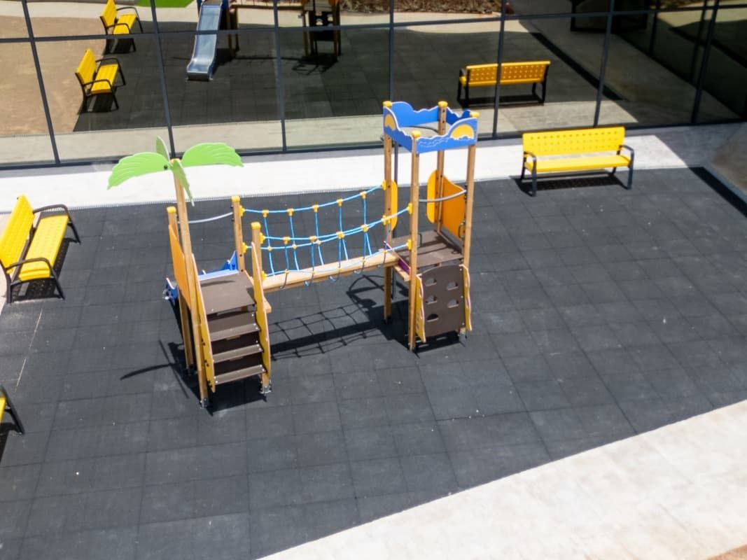 Equipo de juegos con bancos amarillos sobre una superficie gris oscuro.