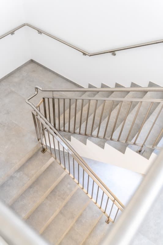 Escalera con escalones de hormigón y pasamanos metálicos vista desde arriba.