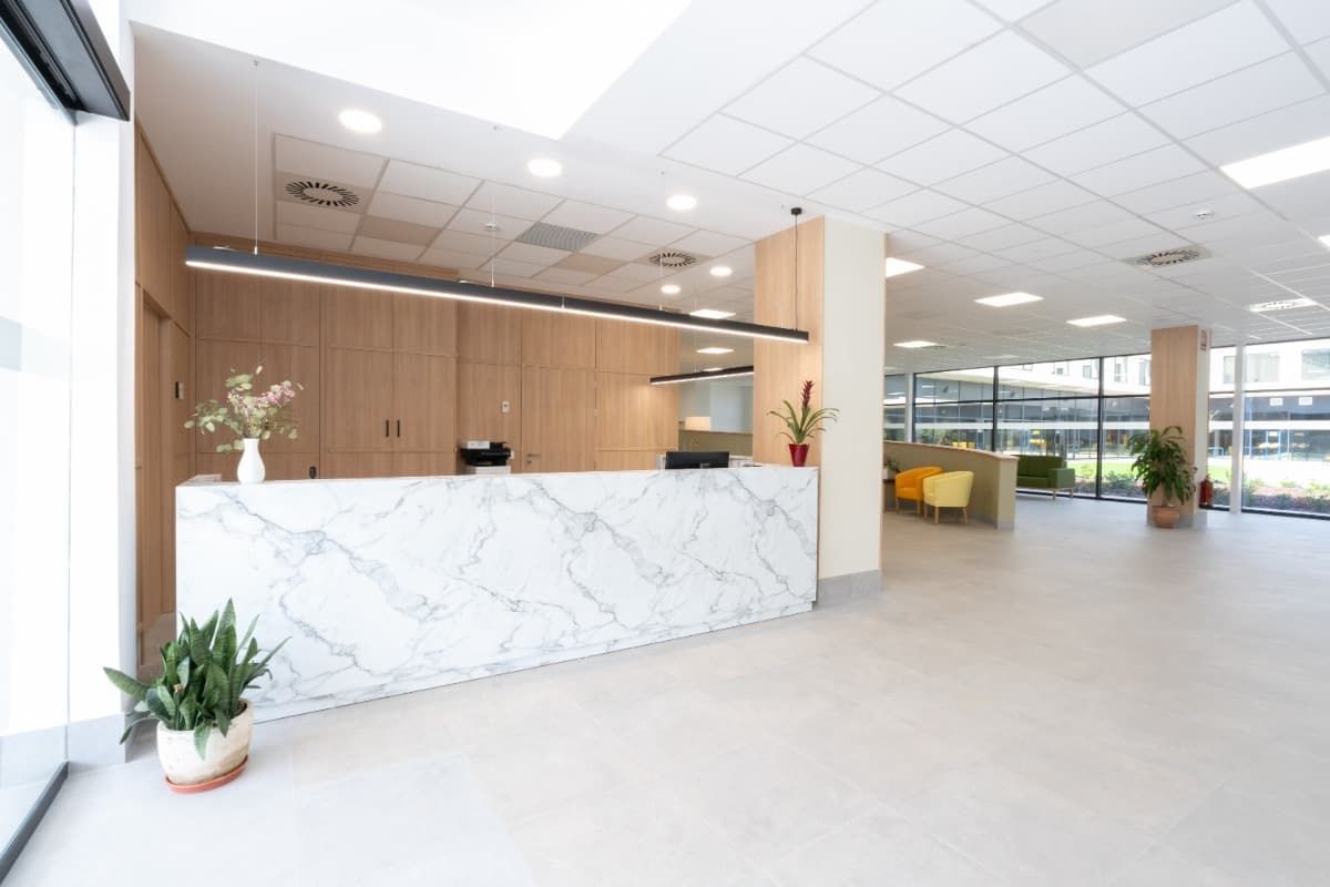 Área de recepción con mostrador de mármol y paneles de madera. Interior con buena iluminación.