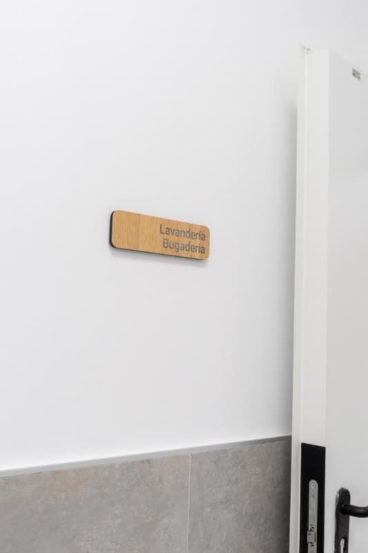 Un cartel de madera sobre una pared blanca dice