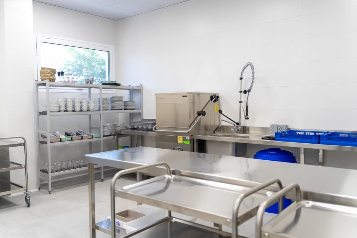 Cocina comercial con mesas, estanterías y equipamiento de acero inoxidable.