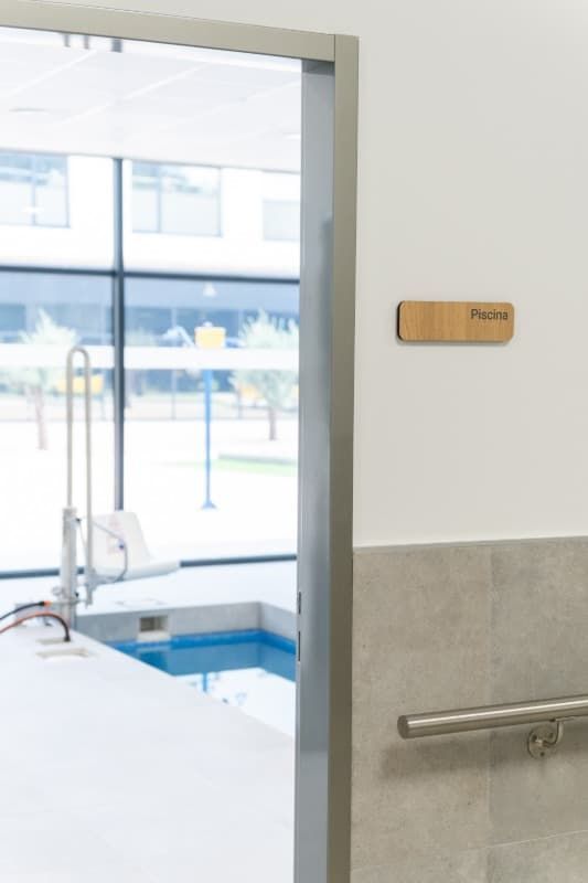 Una sala con una pequeña piscina terapéutica visible a través de una puerta. Un cartel dice