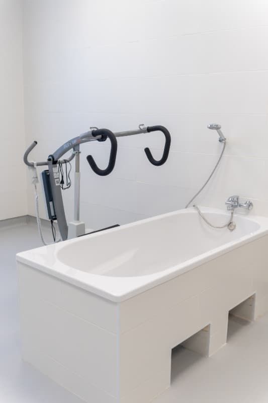 Bañera blanca junto a máquinas de ejercicio en una habitación luminosa.