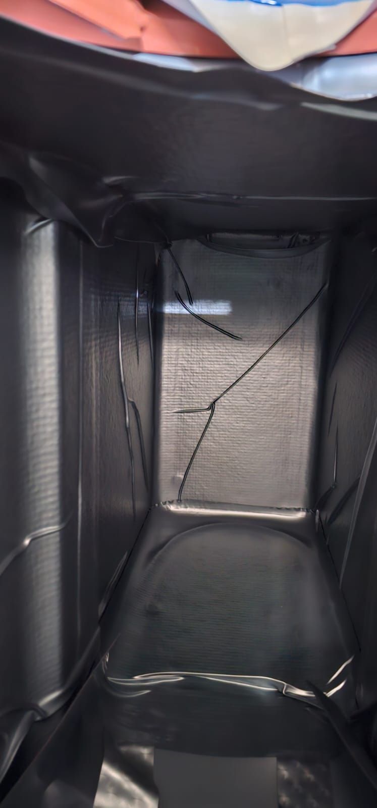 Blick von innen auf eine schwarze, isolierte Liefertasche. Das Innere hat ein reflektierendes Futter und einige sichtbare Risse.