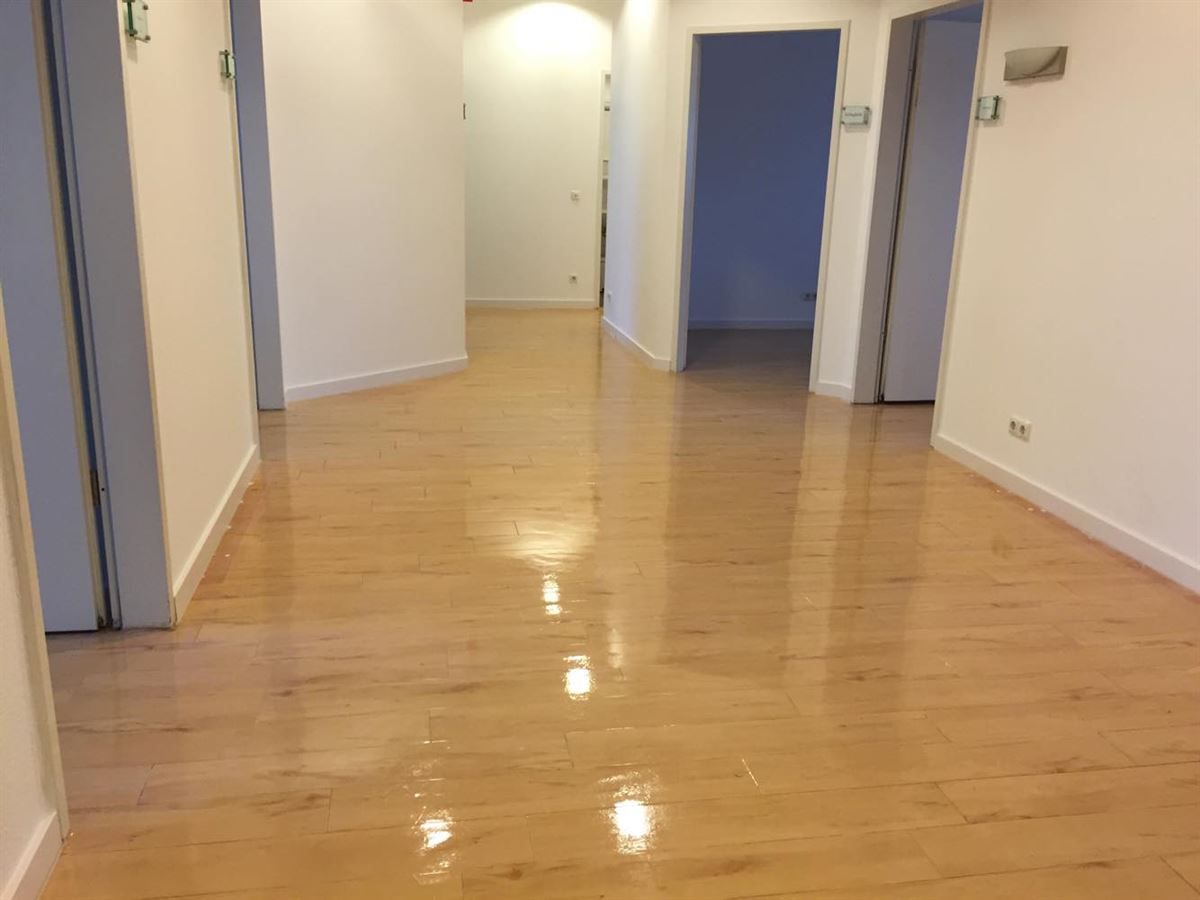 Ein langer Flur mit Holzboden und weißen Wänden.