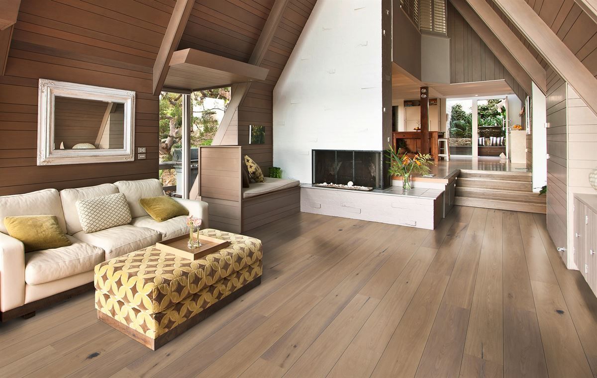 Ein Wohnzimmer mit Parkettboden, Couch und Ottomane