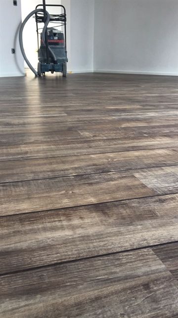 Ein Staubsauger steht auf einem Holzboden in einem Zimmer.