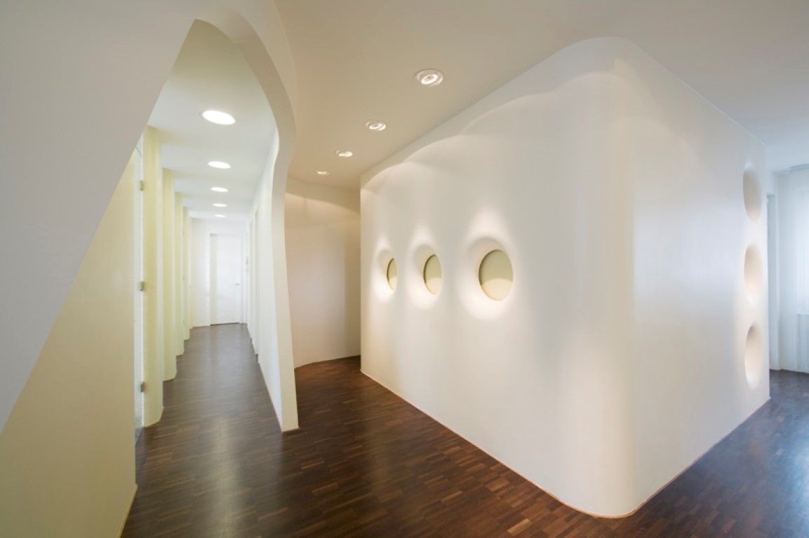 Ein langer Flur mit Holzboden und weißen Wänden.