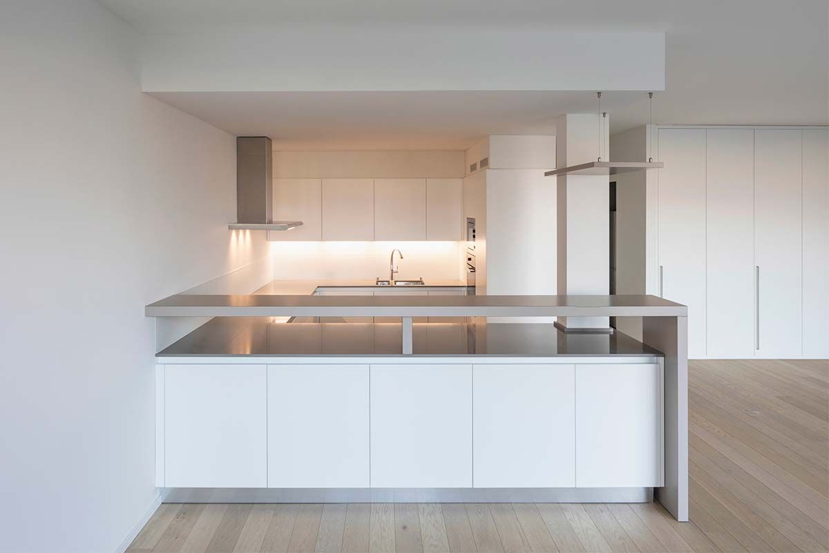 Una cocina vacía con gabinetes blancos y una encimera de acero inoxidable.