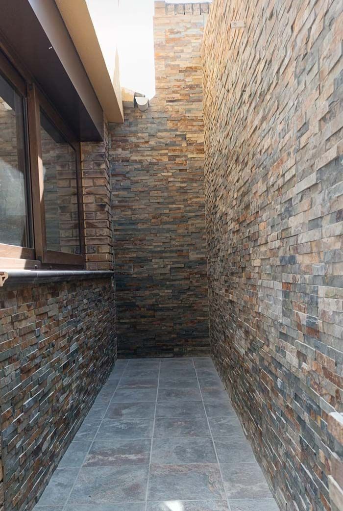 Un pasillo estrecho con una pared de ladrillos y una ventana.