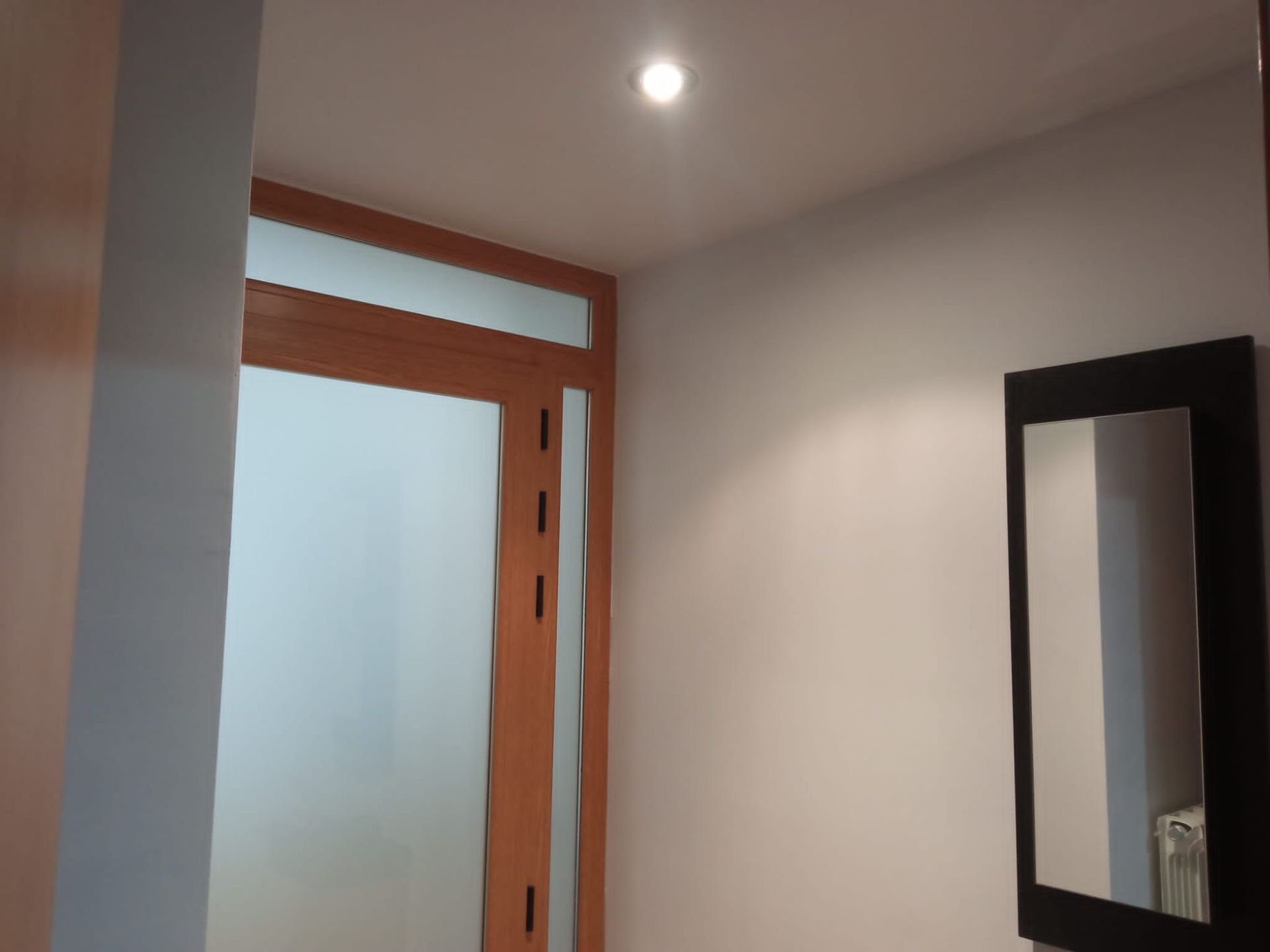 Un pasillo con una puerta y un espejo en la pared.