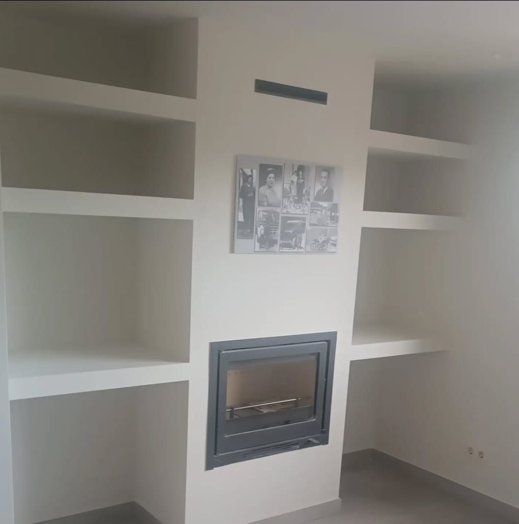 Una chimenea con un cuadro en la pared encima.