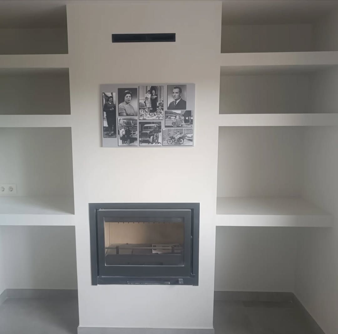 Una chimenea con un cuadro en la pared encima.