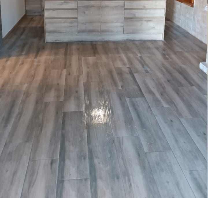 Un suelo de baldosas grises en una habitación con una cocina al fondo.